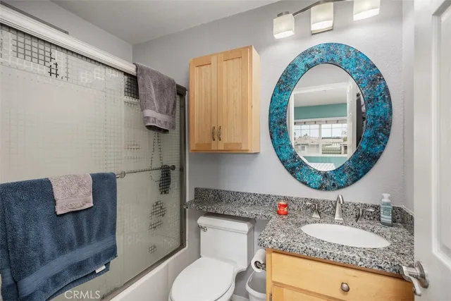 a bathroom with a granite countertop toilet a sink and a mirror