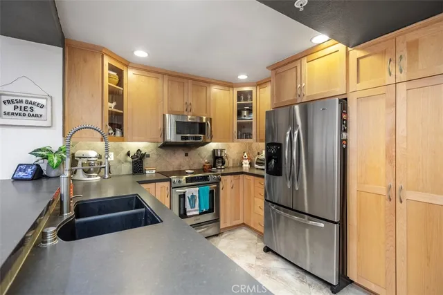 a kitchen with a refrigerator a stove a sink a counter space and cabinets