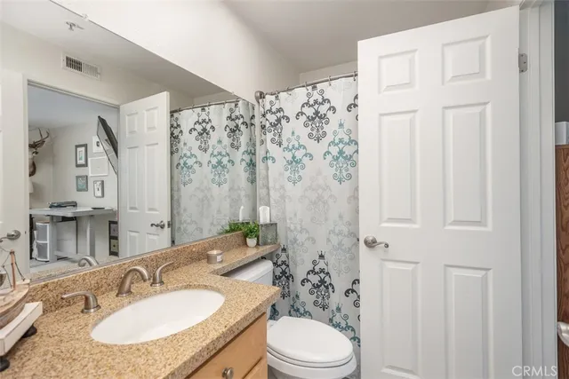 a bathroom with a granite countertop sink a toilet and a mirror