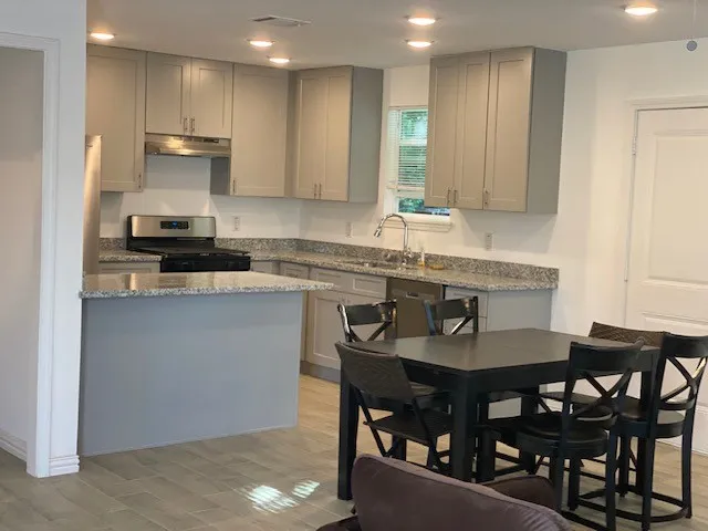 a kitchen with kitchen island granite countertop a sink and white cabinets