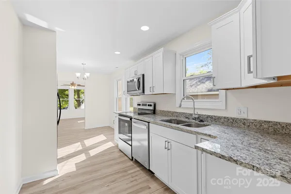 a kitchen with granite countertop cabinets stainless steel appliances a sink and a window