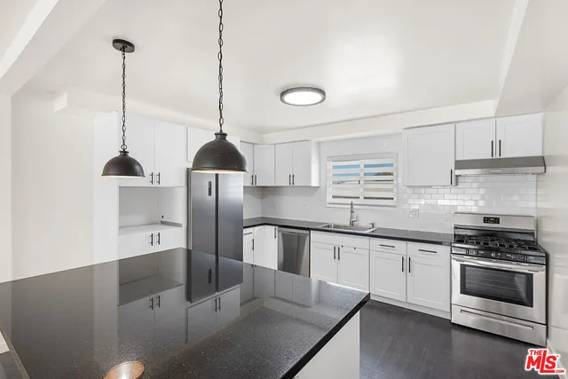 a kitchen with stainless steel appliances granite countertop a sink a stove and refrigerator