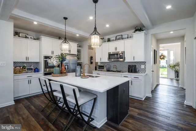 a kitchen with stainless steel appliances kitchen island granite countertop a table chairs sink and cabinets