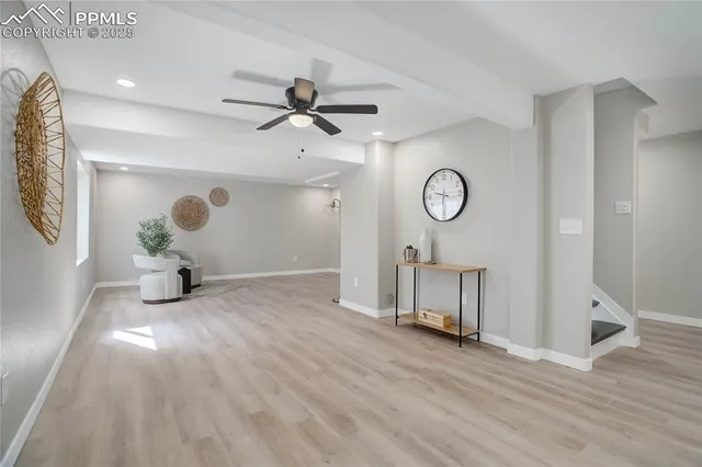 a view of an empty room with wooden floor and a ceiling fan