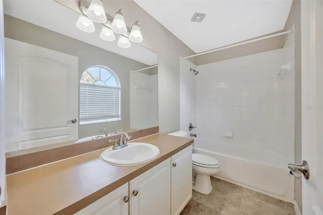 a bathroom with a granite countertop sink a toilet a mirror and shower