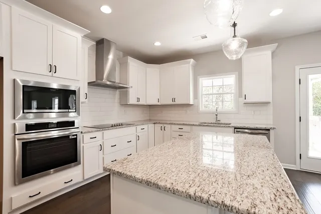 a kitchen with granite countertop a sink stainless steel appliances and white cabinets