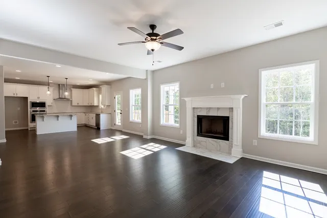 an empty room with wooden floor a kitchen view and a fireplace