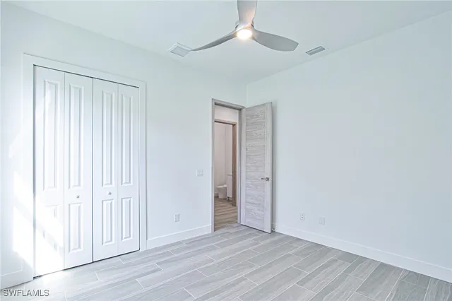 an empty room with wooden floor closet and windows