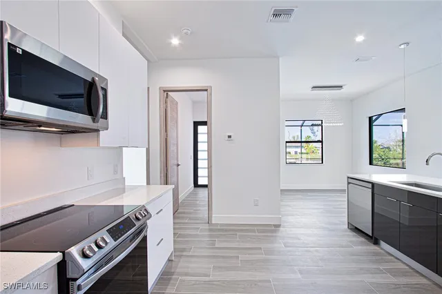 a kitchen with stainless steel appliances granite countertop a stove a sink and a microwave