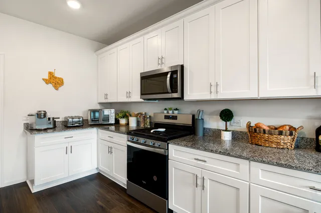 a kitchen with granite countertop white cabinets and white appliances