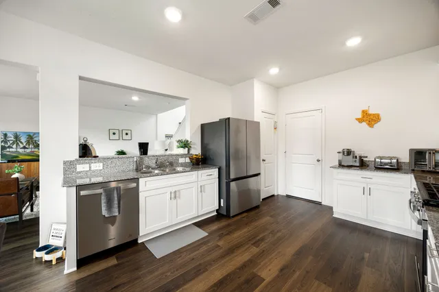 a kitchen with refrigerator a stove and wooden floor