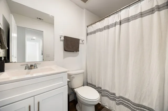 a bathroom with a sink a toilet a mirror and shower curtain