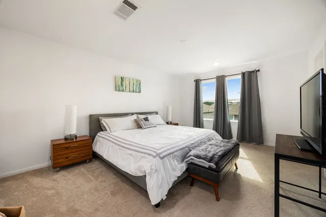 a bedroom with a bed table chair and a flat screen tv