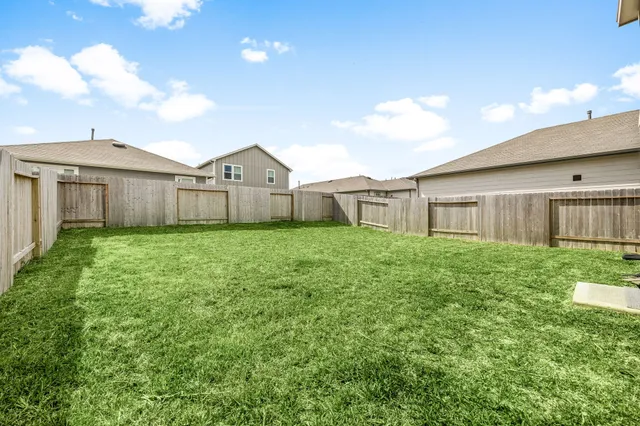 a view of a yard in front of a house with plants and large trees