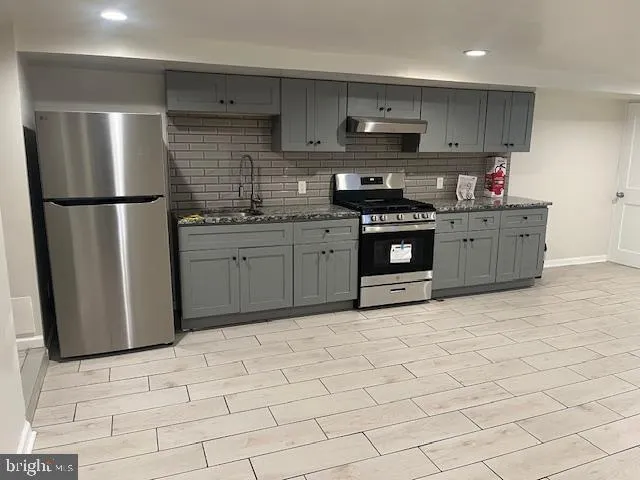 a kitchen with stainless steel appliances granite countertop a refrigerator a stove a sink and a microwave