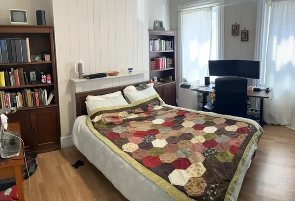 a bedroom with a bed a book shelf and a window