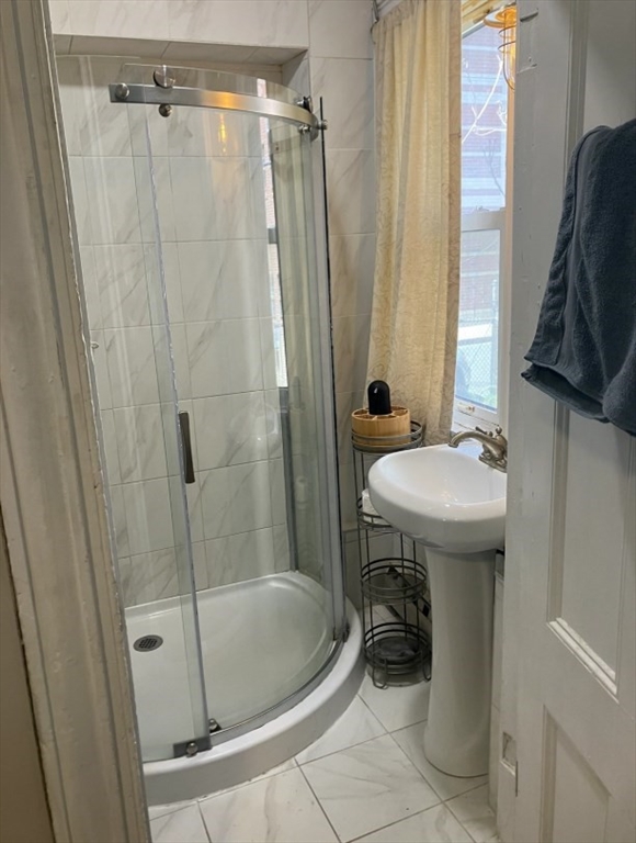 7 Johnny Court, Unit 1 Boston, MA 02111 - Photo 4 of 8 a bathroom with a sink a mirror a bathtub and shower