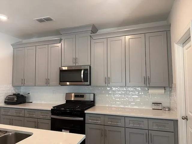 a kitchen with granite countertop white cabinets and black appliances