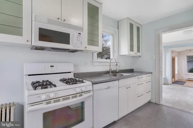 a kitchen with granite countertop white cabinets stove and sink