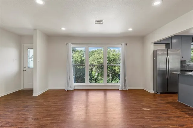 a kitchen with stainless steel appliances granite countertop a refrigerator a sink dishwasher a stove and a wooden floor