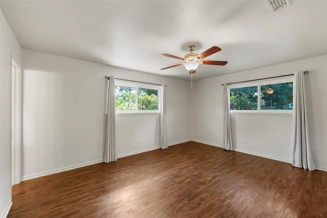 a view of empty room with wooden floor and fan