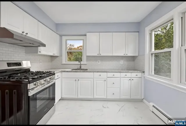 a kitchen with granite countertop white cabinets and window