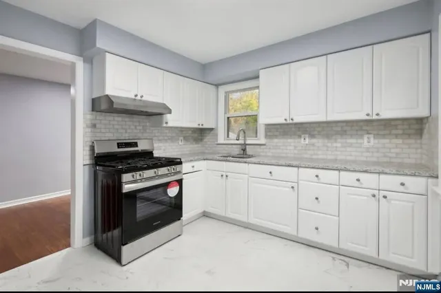a kitchen with stainless steel appliances granite countertop a stove a sink and white cabinets