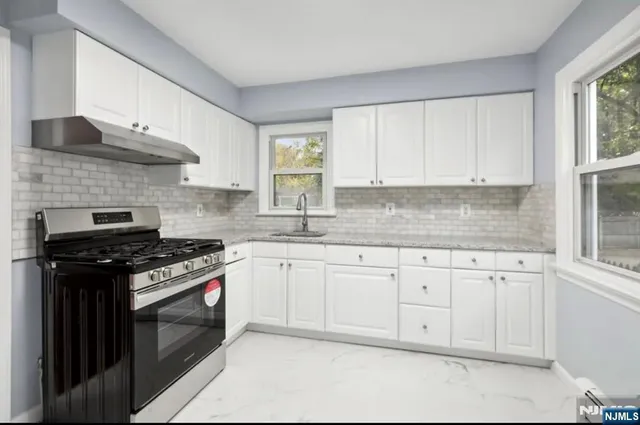 a kitchen with granite countertop white cabinets and stainless steel appliances