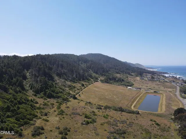 a view of a dry field with mountains in the background