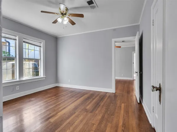 a view of empty room with wooden floor and fan