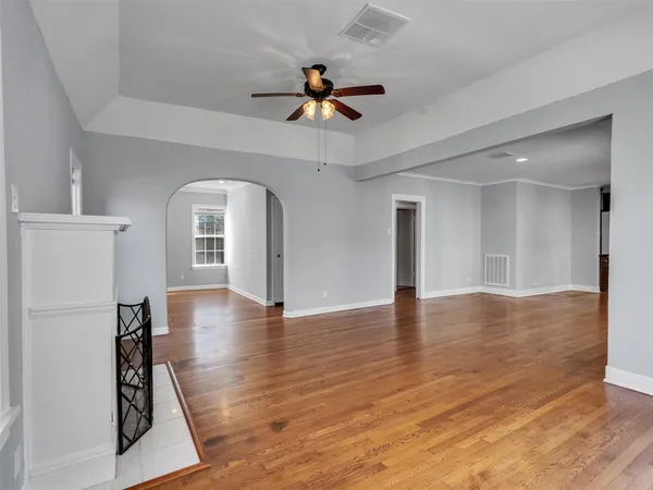 a view of empty room with wooden floor and ceiling fan