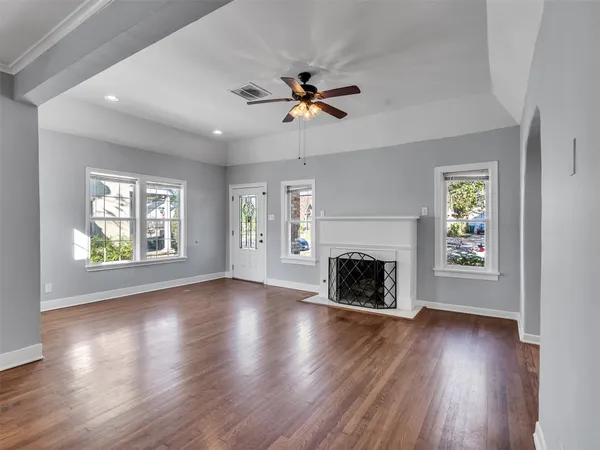 an empty room with windows fireplace and wooden floor