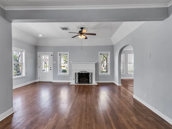 an empty room with wooden floor fireplace and windows