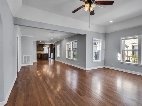 a view of an empty room with window and wooden floor