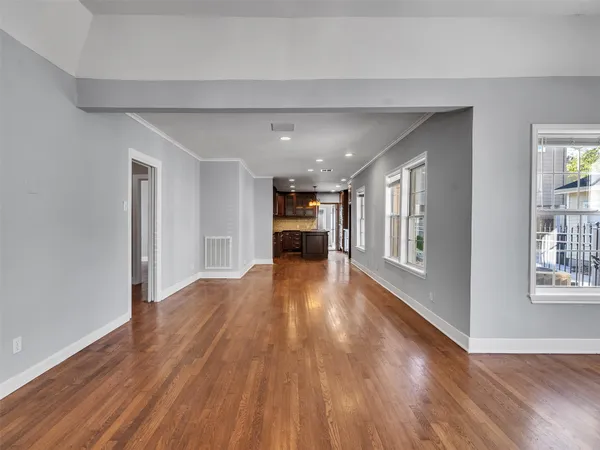 a view of empty room with wooden floor and windows