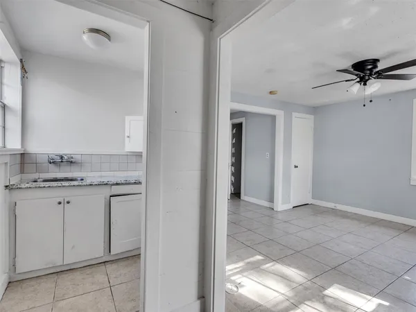 a view of an empty room with window and chandelier fan