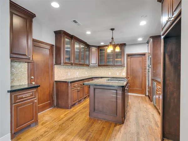 a kitchen with stainless steel appliances granite countertop a refrigerator a stove and a wooden floors