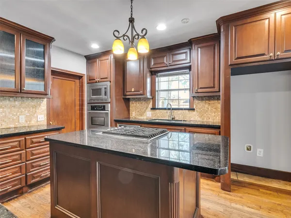 a kitchen with granite countertop a stove a sink and a refrigerator