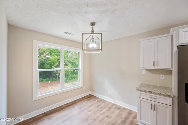 an empty room with wooden floor cabinet and windows