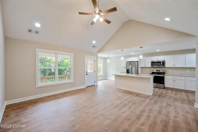 a large kitchen with stainless steel appliances kitchen island a large counter top and a wooden floors