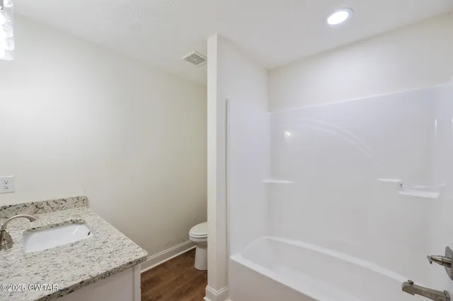 a bathroom with a granite countertop sink and toilet