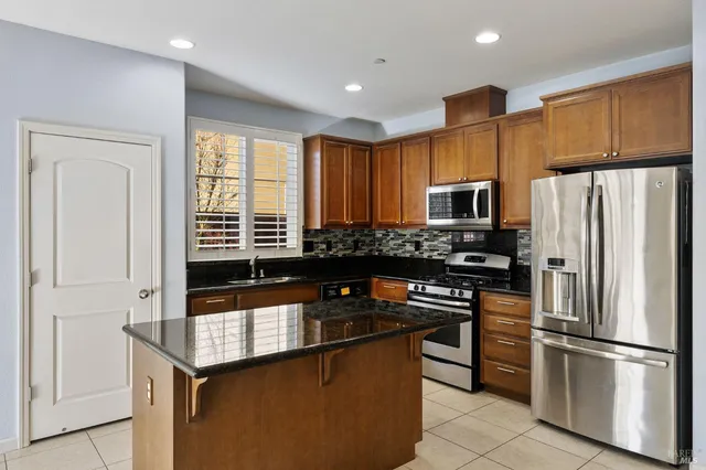 a kitchen with stainless steel appliances granite countertop a refrigerator and a stove top oven