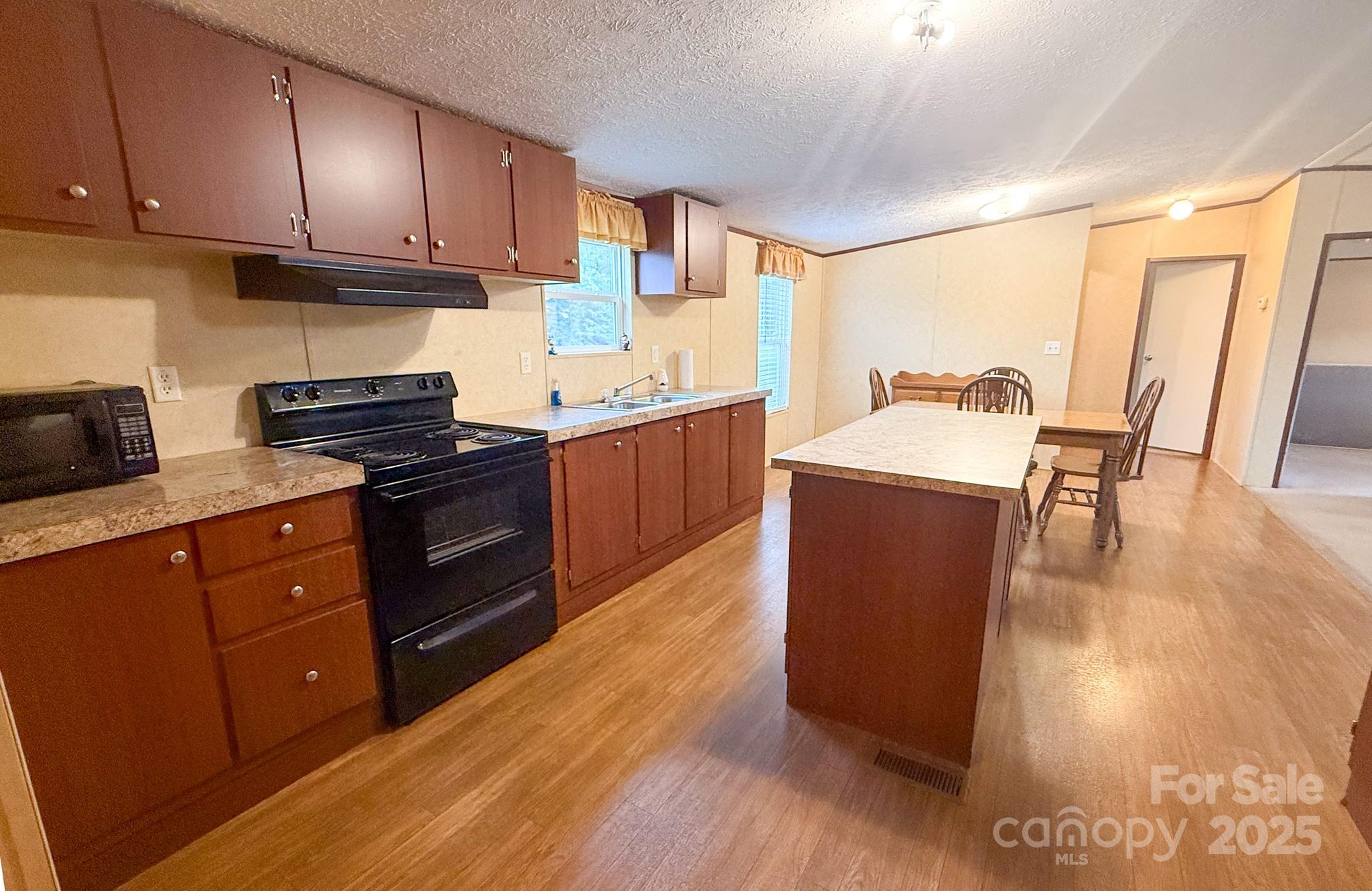 4559 Union Highway Gaffney, SC 29340 - Photo 9 of 23 a kitchen with stainless steel appliances granite countertop a stove a refrigerator a sink a dining table and chairs with wooden floor
