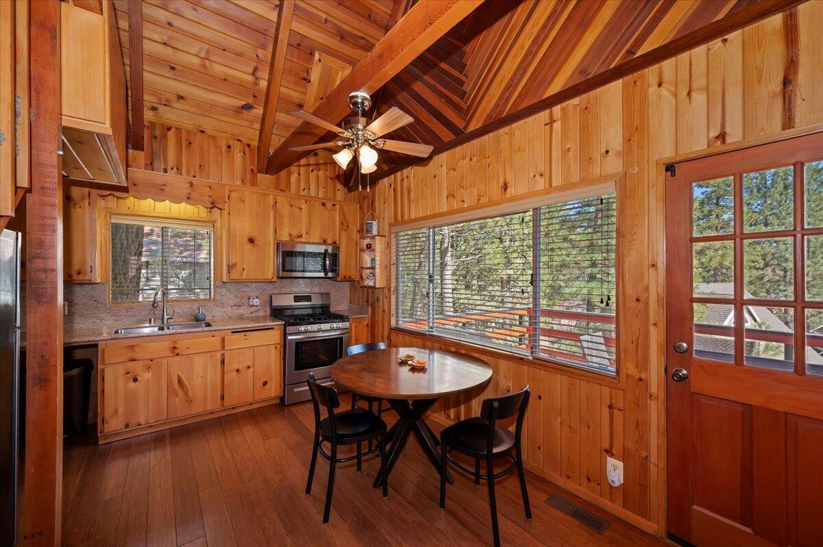 39187 Arapahoe Road Fawnskin, CA 92333 - Photo 10 of 33 a kitchen with stainless steel appliances granite countertop a stove a refrigerator a sink dishwasher a dining table and chairs with wooden floor
