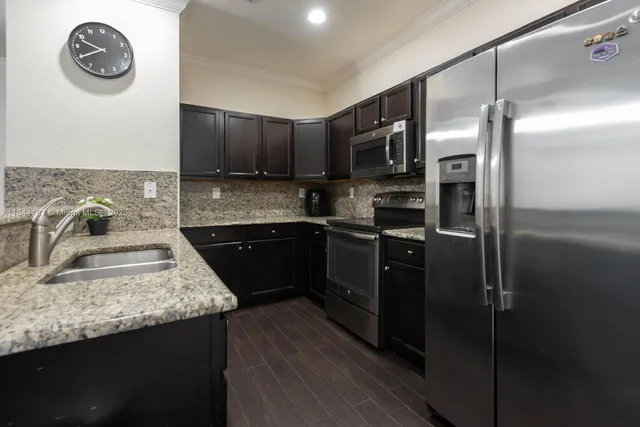 a kitchen with kitchen island granite countertop a sink cabinets and stainless steel appliances