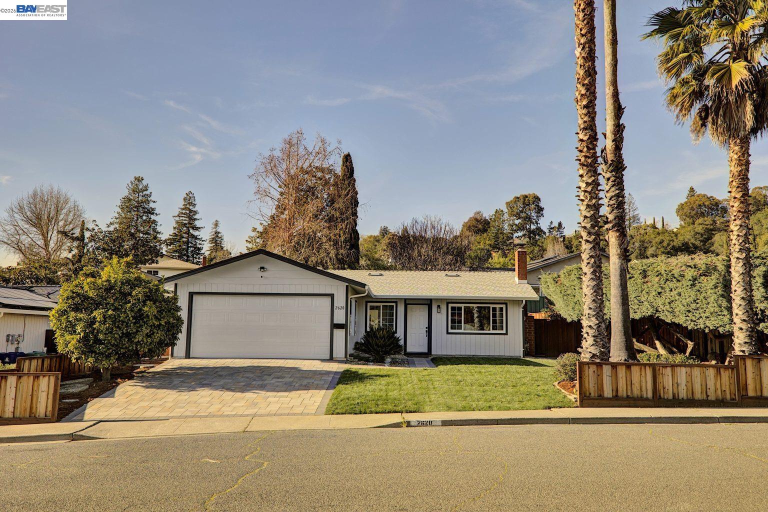 a front view of a house with a garden and tree