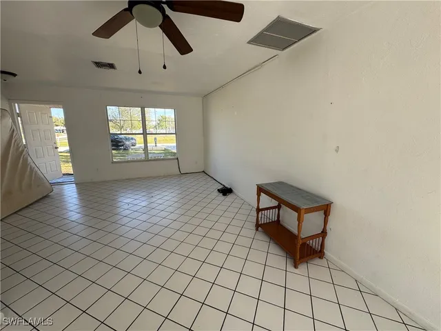 an empty room with windows and ceiling fan