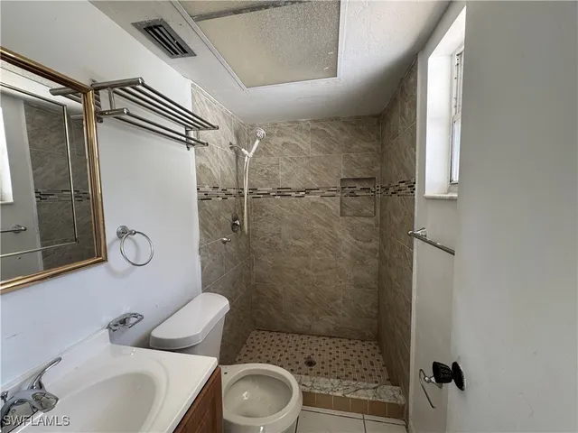 a bathroom with a sink a toilet a mirror and shower