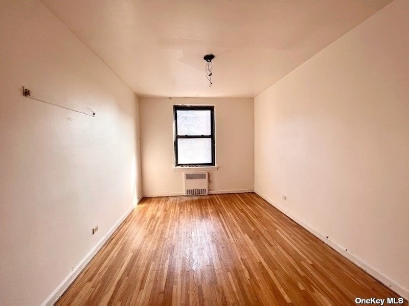 112-24 Northern Boulevard, Unit 4B Queens, NY 11368 - Photo 4 of 9 an empty room with wooden floor chandelier and windows