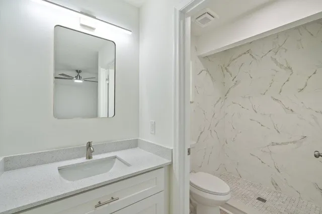 a bathroom with a granite countertop sink a toilet and a mirror